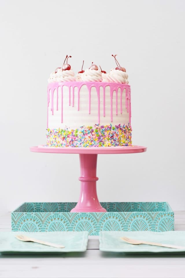 Bolo de aniversário com cobertura rosa e cerejas